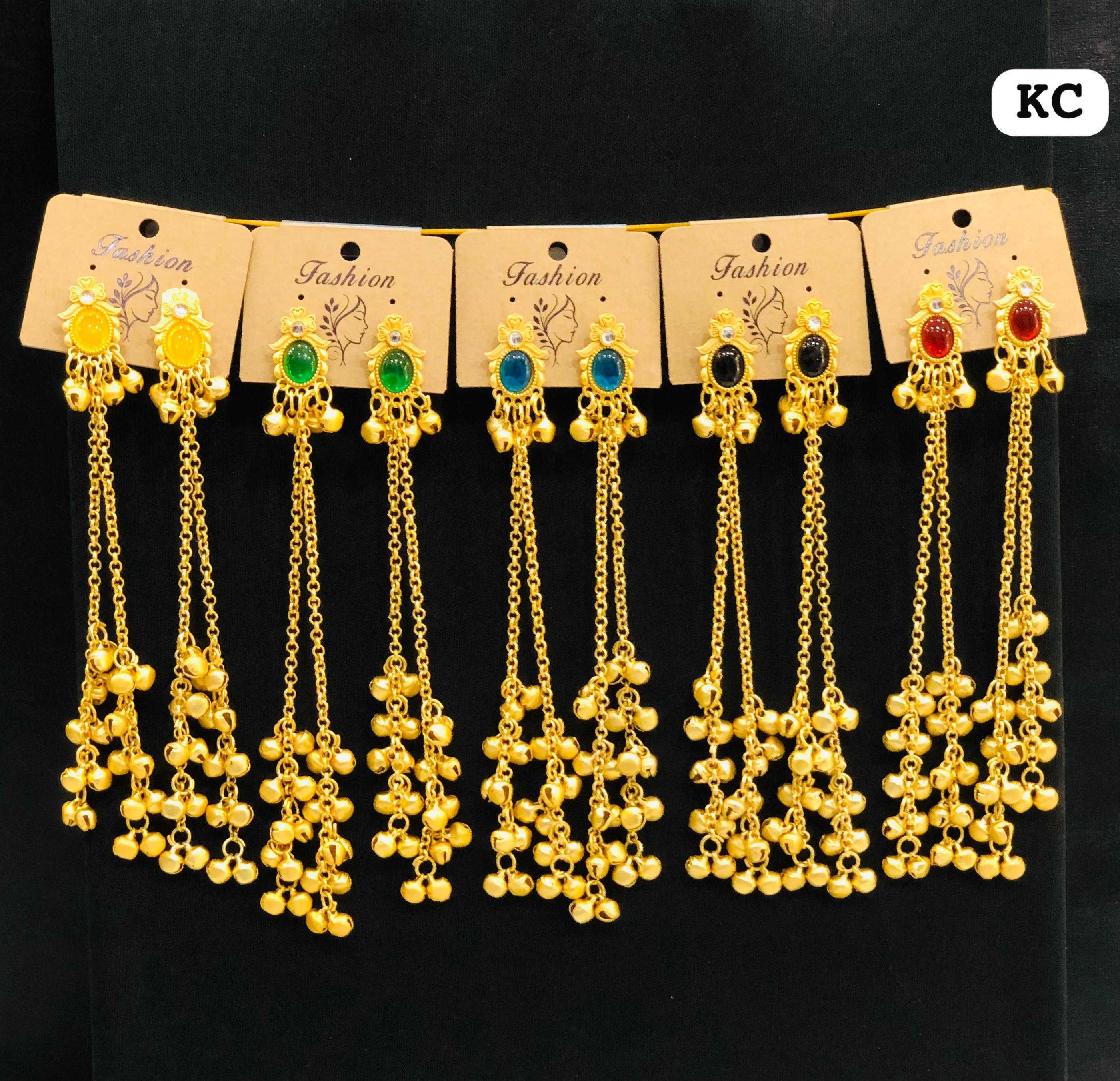 A display of five pairs of gold-plated earrings featuring yellow, green, blue, black, and red oval gemstones with long cascading bell chains.