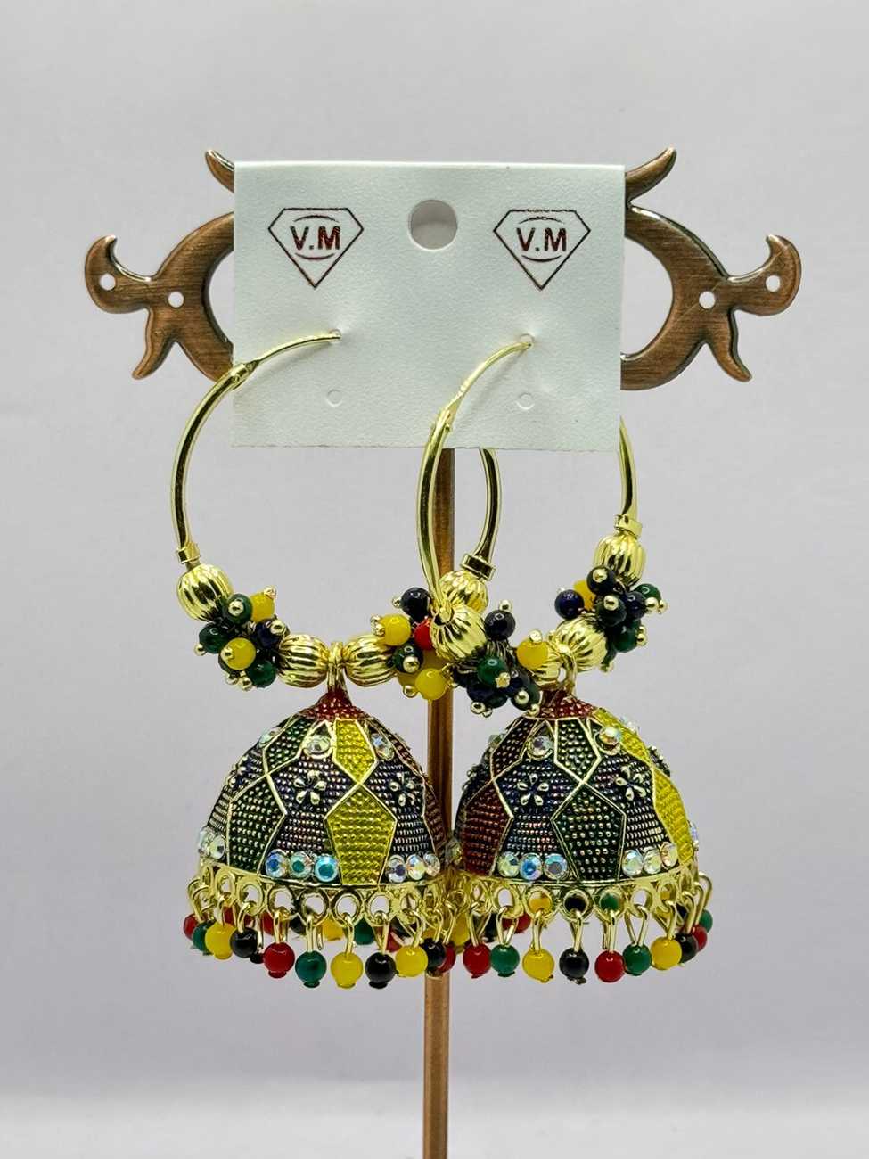A pair of ornate traditional earrings with intricate metalwork and colorful bead details displayed on a stand with a white background.