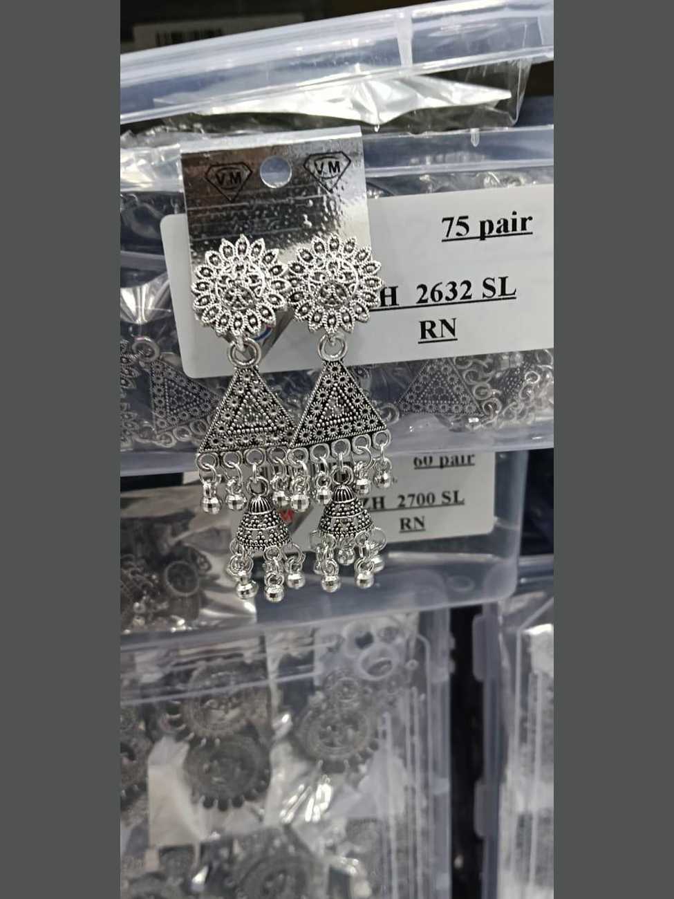 Oxidized silver earrings featuring a large floral stud, a triangle with geometric filigree, and cascading jhumka bells.